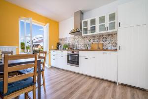 a kitchen with white cabinets and a table and chairs at FeWo Haus kleine Müritz in Rechlin