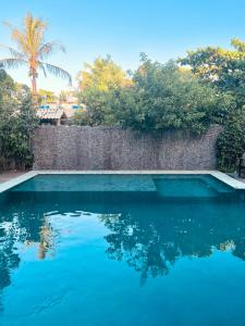 a swimming pool with blue water in front of a wall at Pousada Mangue Sereno in Caraíva