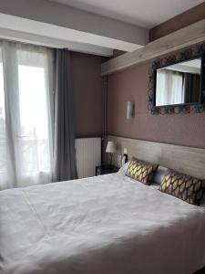um quarto com uma grande cama branca e um espelho em Hostellerie Saint Clément em Vic-sur-Cère