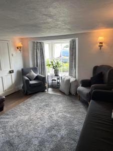 a living room with a couch and chairs and a window at Myrtle Cottage Boscastle in Boscastle