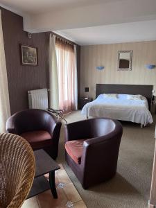 pokój hotelowy z łóżkiem i 2 krzesłami w obiekcie Hostellerie Saint Clément w mieście Vic-sur-Cère
