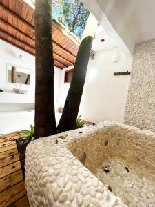 Habitación con sofá de piedra y árbol en Pousada Mangue Sereno, en Caraíva