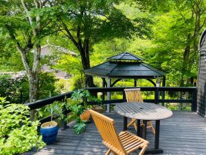 una terraza de madera con mesa, sillas y cenador en Foresta Karuizawa 1, en Oiwake