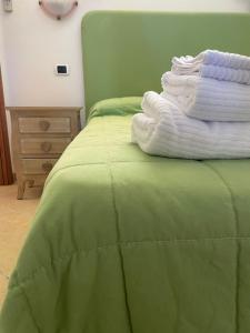 - une pile de serviettes assises au-dessus d'un lit vert dans l'établissement Le Palme Bed And Breakfast, à Briatico