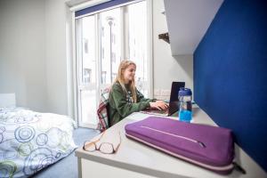 um homem sentado numa secretária com um computador portátil em Ensuite Bedrooms with Shared Kitchen at Bay Campus located in Swansea em Swansea