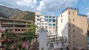 un groupe de bâtiments avec des montagnes en arrière-plan dans l'établissement Around Stays Hostel Rishikesh, Tapovan, à Rishikesh