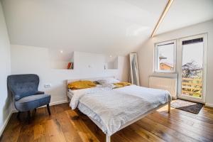 a bedroom with a bed and a chair and a window at Mountain View Apartment with Sauna in Cerklje na Gorenjskem