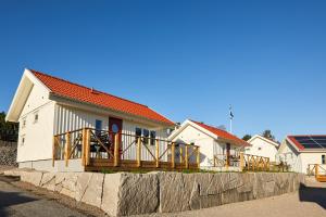 a white house with a porch and a fence at Lagunen Cottages and Hostel in Strömstad