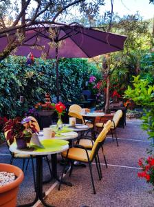 eine Terrasse mit Tischen, Stühlen und einem Sonnenschirm in der Unterkunft Hotel Virginia in Garda