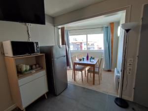 kuchnia z lodówką i stołem z kuchenką mikrofalową w obiekcie SOPRALAND Joli T2 piscine proche plage Richelieu Cap d'Agde w Cap d'Agde +5 zdjęć