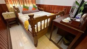 a bedroom with a wooden bed and a table with a television at Okay 1 Villa in Siem Reap