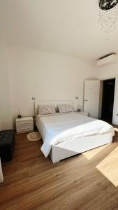 Habitación blanca con cama blanca grande y suelo de madera. en CASA ISABEL, en Cadelbosco di Sopra