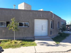 um edifício com uma porta de garagem branca e uma árvore em Casa ROCIO em Chimbas