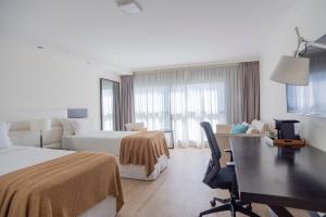um quarto de hotel com duas camas e uma secretária em After Hotel Montevideo em Montevidéu