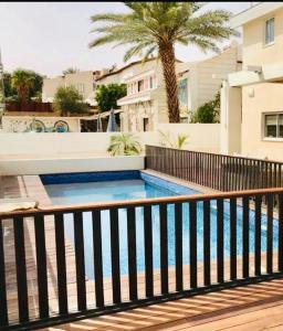 a swimming pool with a fence and a palm tree at Glamour Luxury Suite Swimming pool in Eilat