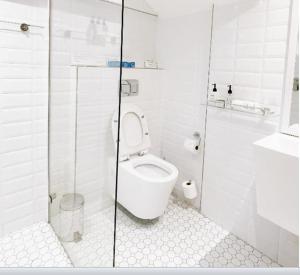 a white bathroom with a toilet and a shower at Sugar Hotel in Cape Town