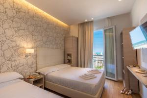 a hotel room with two beds and a television at Hb Hotels Orchidea Blu in Rimini