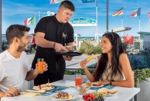 a man holding a plate of food at a table at Hb Hotels Orchidea Blu in Rimini