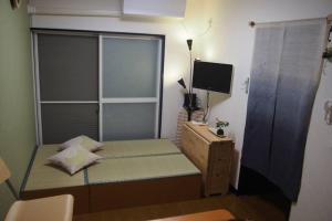 a small bedroom with a bed and a television at Love Kyoto Kyoenkan in Kyoto