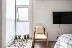 una camera da letto con sedia e TV a parete di Increible departamento en la del valle a Città del Messico