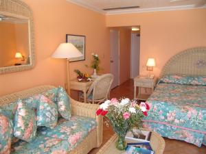 Habitación de hotel con cama, sofá y flores en Coco Reef Bermuda en Mount Pleasant