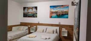 2 Betten in einem Zimmer mit Gemälden an der Wand in der Unterkunft IL CENTRO LUXURY SUITES in Bari