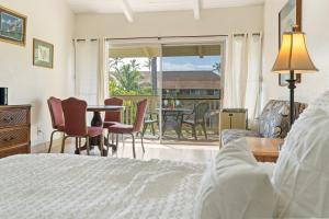 a bedroom with a bed and a table and chairs at Kihei Bay Surf B212 in Kihei +7 photos