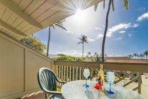 a table with two wine glasses on a balcony at Kihei Bay Surf B212 in Kihei