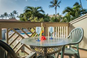 a table with a bottle of wine and two glasses at Kihei Bay Surf B212 in Kihei