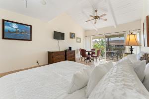 a bedroom with a bed and a television and a table at Kihei Bay Surf B212 in Kihei