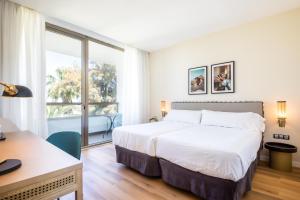 a bedroom with a bed and a desk and a window at Hotel Barú in Sagunto