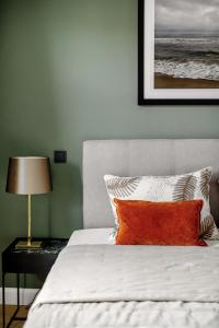 a bedroom with a bed with an orange pillow at Living Lorens No 2 in Westerland (Sylt)