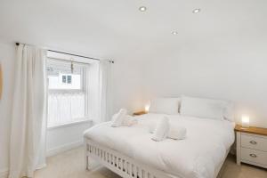 彭贊斯的住宿－Copper Bal Cottage，白色的卧室设有白色的床和窗户。