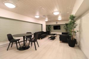 poczekalnia ze stołami i krzesłami oraz kanapą w obiekcie Forenom Aparthotel Helsinki Herttoniemi w Helsinkach