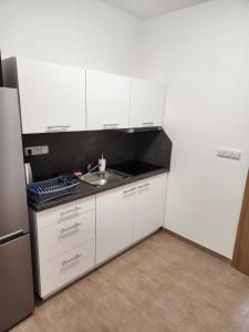 a kitchen with white cabinets and a sink and a refrigerator at Ubytování Janovice nad Úhlavou, Rozvojová zóna 186 in Janovice nad Úhlavou