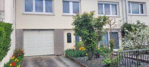 a house with a white garage door and flowers at Studio chaleureux avec parking gratuit in Vandoeuvre-lès-Nancy