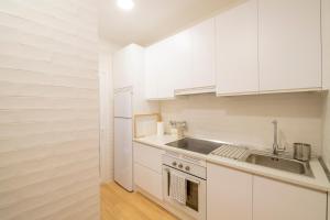 una cocina con armarios blancos y fregadero en Apartamento Tomillo I, en Candeleda