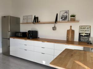cocina con armarios blancos y nevera de acero inoxidable en Moderne 70 qm Ferienwohnung in Waldrandlage, en Eppelborn