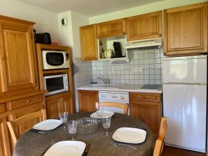 eine Küche mit einem Tisch und einem weißen Kühlschrank in der Unterkunft Appartement Samoëns, 2 pièces, 5 personnes - FR-1-624-37 in Samoëns