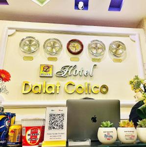 einen Tisch mit einem Laptop und Uhren an der Wand in der Unterkunft Dalat Colico Hotel in Da Lat