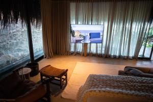 uma sala de estar com uma cama e uma televisão em Paru Boutique Hotel em São Miguel dos Milagres