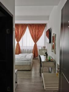 a bedroom with a bed and a desk and a window at Nevis Fundeni in Bucharest