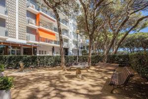 un parco con panchine e alberi di fronte a un edificio di Apartamento Condal a Blanes