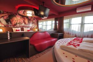 a hotel room with a bed and a red chair at Hotel Corvin in Gyula