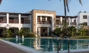 a villa with a swimming pool in front of a building at TULIA BEACH HOUSE, AT SULTAN PALACE in Kilifi