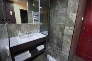 a bathroom with a white sink and a shower at Hotel Corvin in Gyula