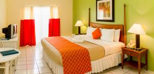 a bedroom with a large bed with red curtains at Bay Gardens Inn in Gros Islet