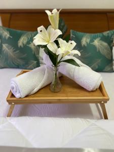 a vase of flowers sitting on a table with towels at Batu Pahat Qastina Gunong Soga Homestay in Batu Pahat