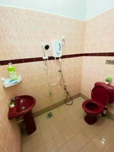 een badkamer met een rood toilet en een wastafel bij Batu Pahat Qastina Gunong Soga Homestay in Batu Pahat