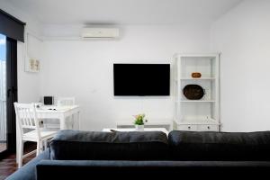 - un salon avec un canapé et une télévision murale dans l'établissement Apartamento White Sun, à Playa Honda